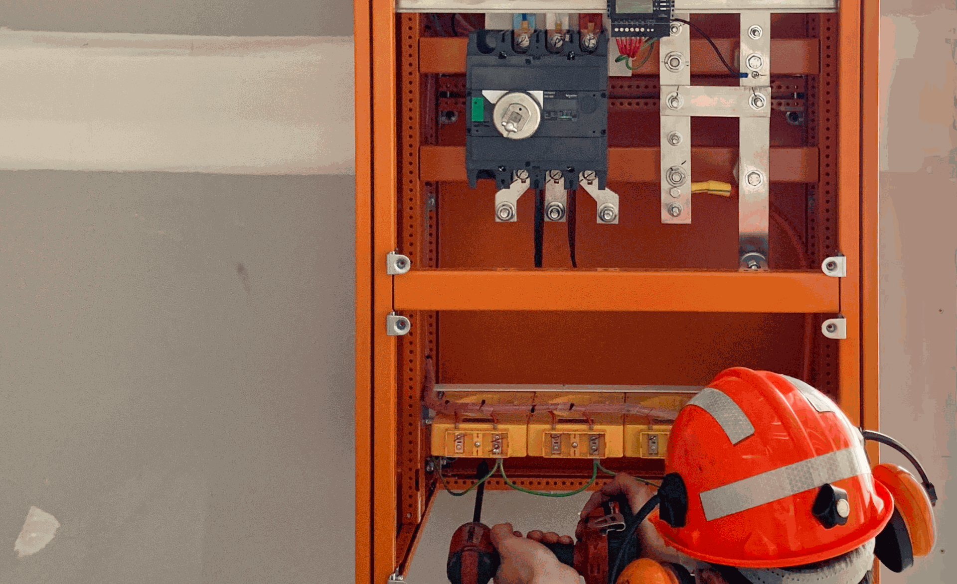 Electrician working inside an open switchboard during commissioning